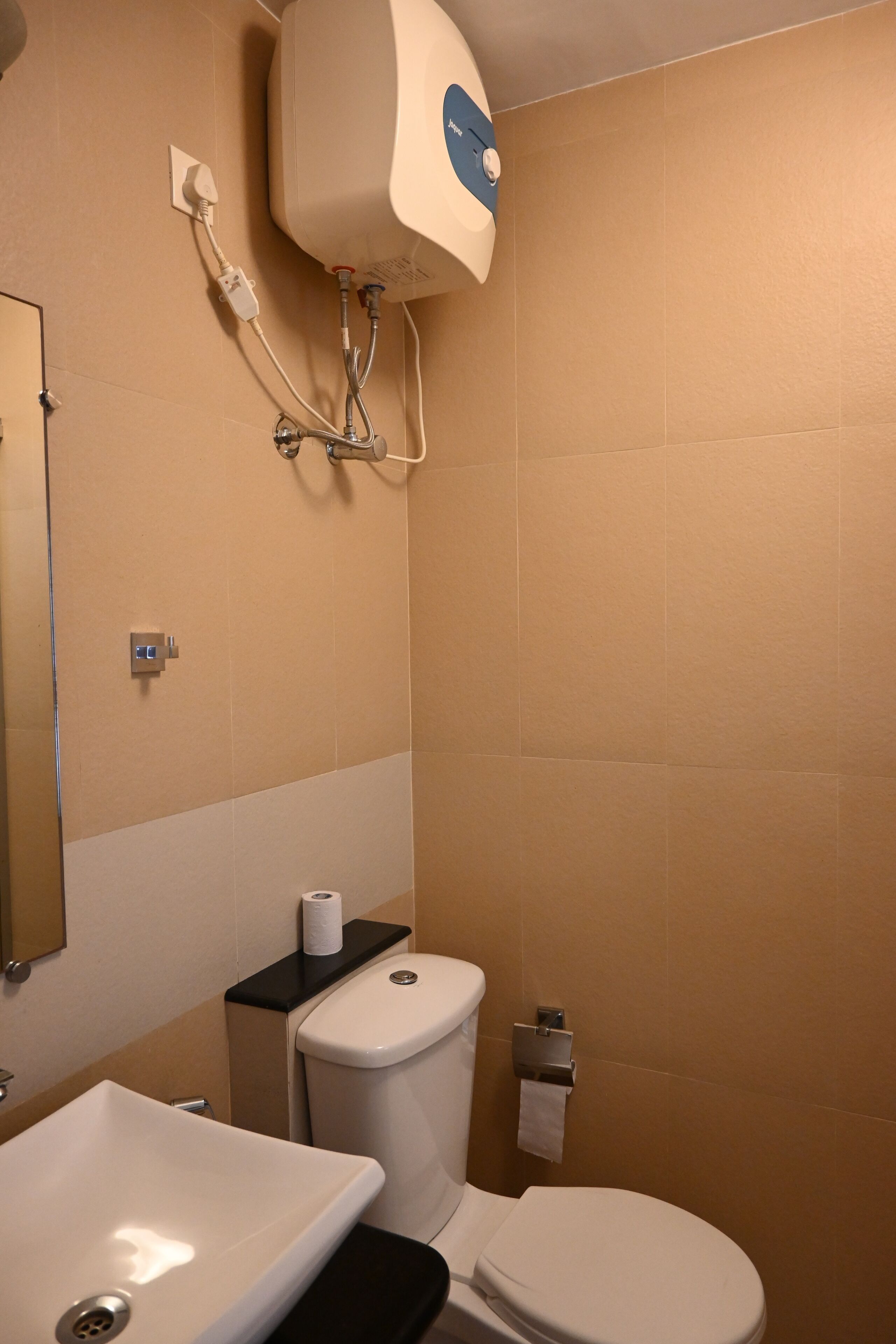 A bathroom with a toilet, sink, and a wall-mounted water heater.