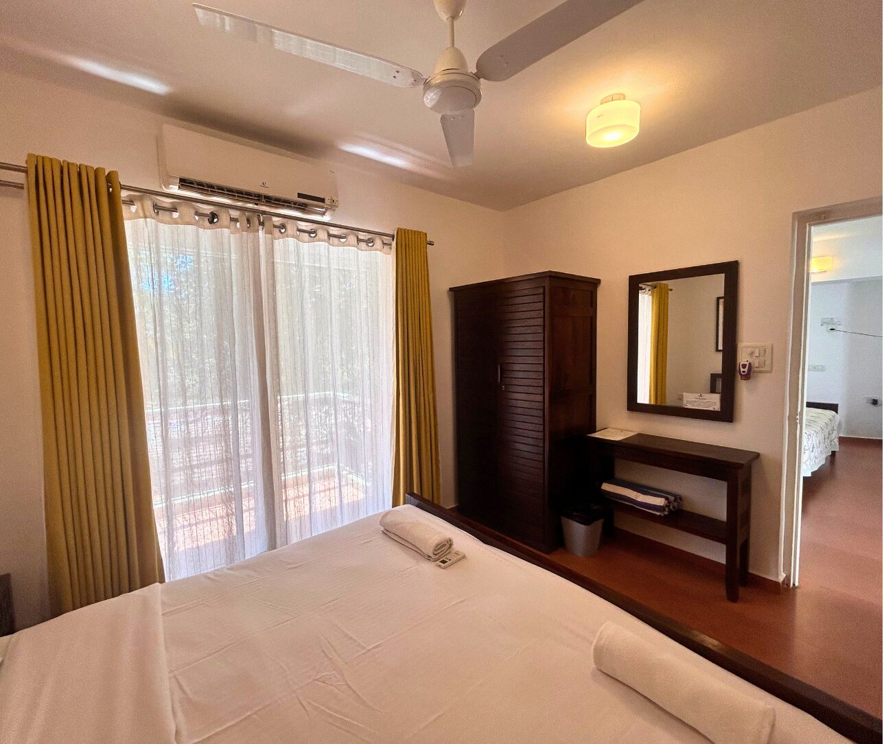 Habitación de hotel con cama, armario, escritorio con espejo y equipo de aire acondicionado.