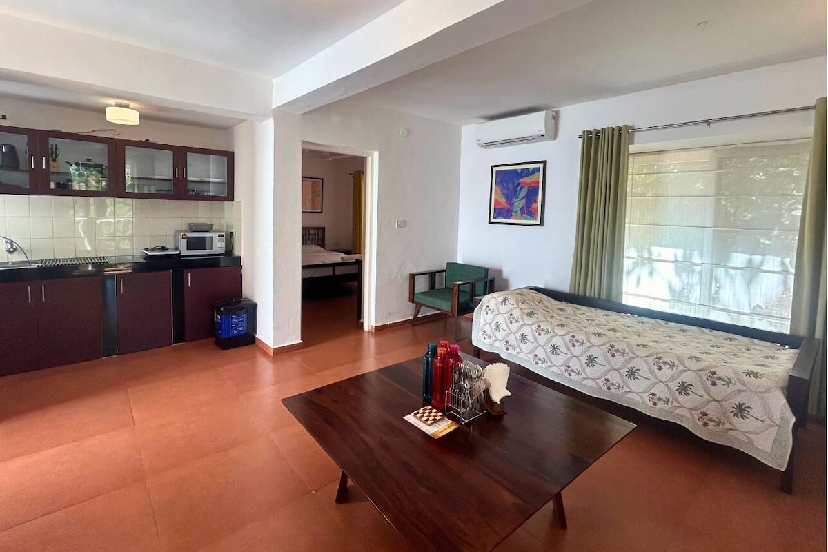 A compact living space with a kitchenette, a dining area, and a bedroom.