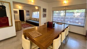 A dining area with a wooden table, six chairs, and a ceiling fan. - Jungle Hut- Annabelles Beach Apartments at Bernard Simao Calangute (Calangute)