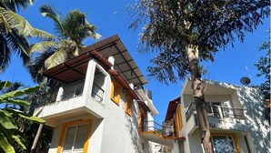 Un edificio residencial de varios pisos con balcones, rodeado de follaje tropical.