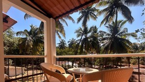 Un balcón con mobiliario de mimbre y vistas a palmeras.