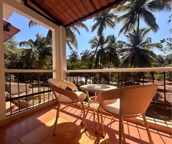 Un balcón con mobiliario de mimbre y vistas a palmeras.