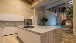 Una cocina moderna con una isla central, electrodomésticos integrados y vistas a una piscina.