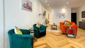 Ein modernes Wohnzimmer mit Fischgrätparkett, zwei Sofas, einem Couchtisch und einem an der Wand befestigten Fernseher.