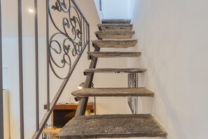 Stunning staircase with a unique blend of traditional and contemporary elements, featuring ornate metal railings and a rustic stone design.