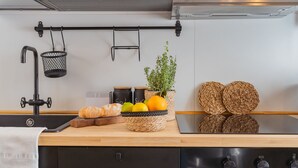 A kitchen with a wooden countertop, a sink, a black faucet, a basket of fruits, a loaf of bread, and woven coasters. - Via Muralto 13 in Como (Como)