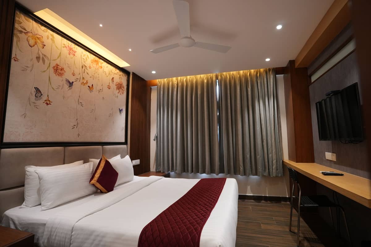 A hotel room with a bed, a desk, a television, and a ceiling fan.