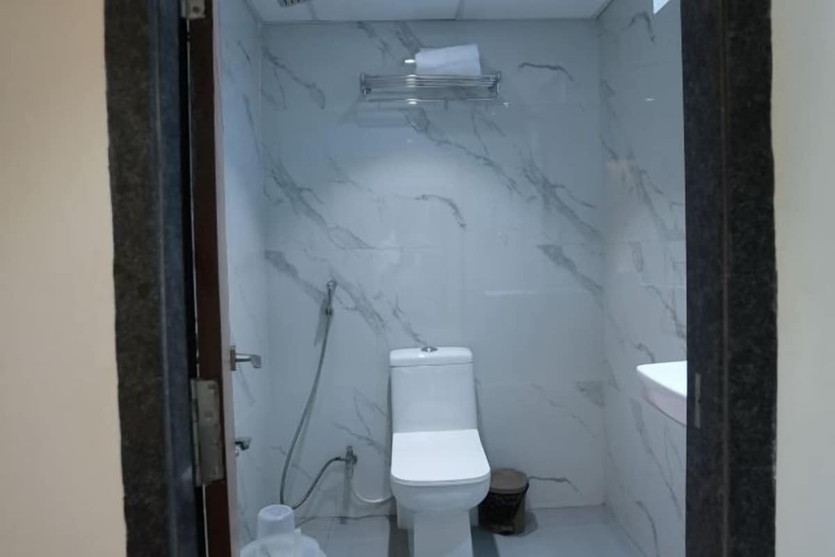 A bathroom with a toilet, a sink, a shower, and a marble wall.
