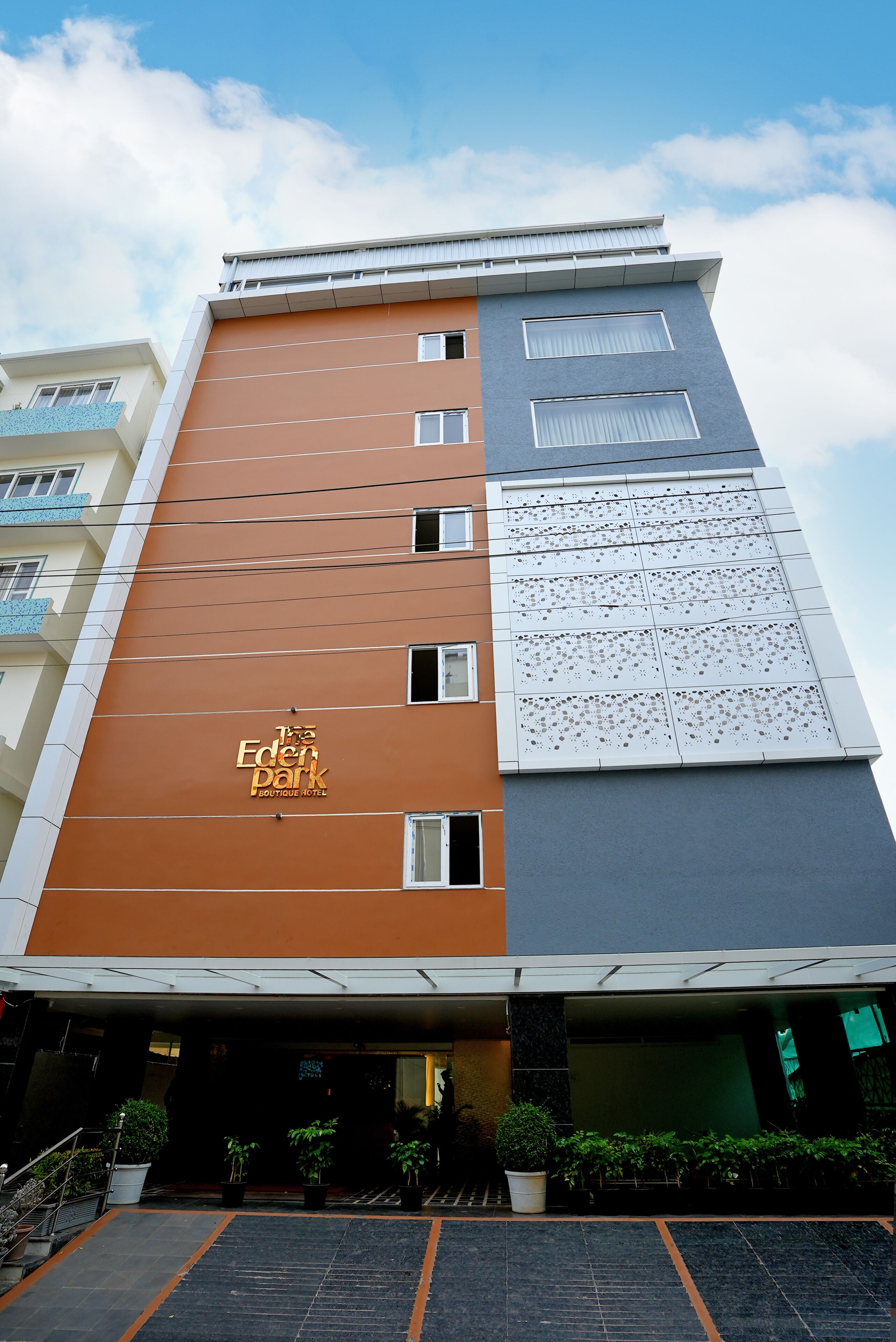 A multi-story hotel with a prominent orange facade and a sign reading "The Eden Park Boutique Hotel."