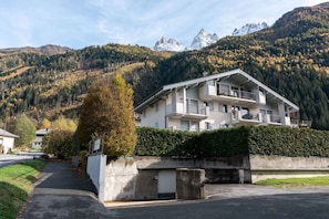 Un hotel su due piani con balconi, un'area di parcheggio e vista sulle montagne.
