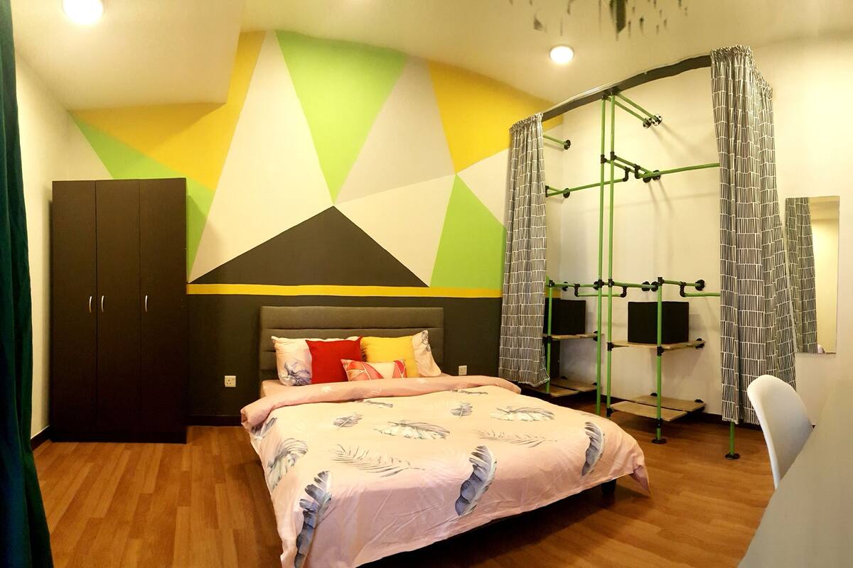 A bedroom with a bed, a wardrobe, a desk, and a chair.