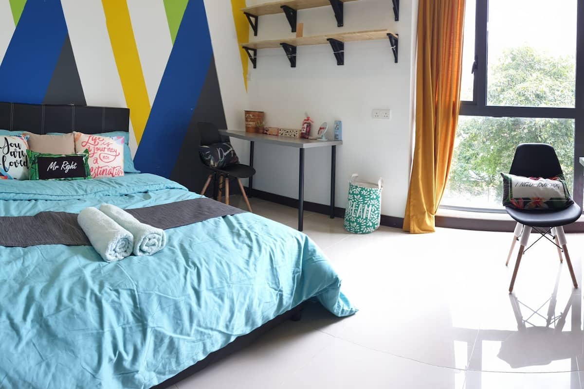 A bedroom with a bed, a desk, a chair, and a window.