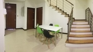 A dining area with a table and chairs, a staircase, and a door. - Industrial Suites at Bandar Sunway (Petaling Jaya)