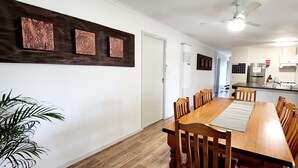 A dining area with a wooden table and chairs, a ceiling fan, and artwork on the wall. - Port of Sale, town centre 5KM drive (Wurruk)
