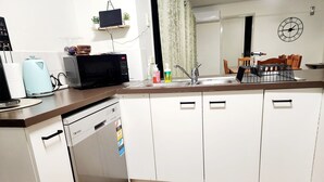 A compact kitchen with white cabinets, a microwave, a dishwasher, and a small countertop area. - Port of Sale, town centre 5KM drive (Wurruk)