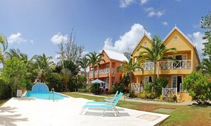 A resort with a swimming pool, two-story buildings, and palm trees. - Villa located in St James on the west cost of Barbados with sea view and pool. (Fitts Village)