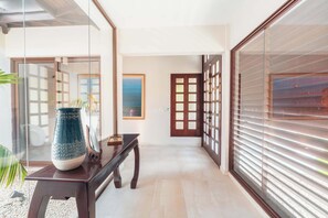 Un couloir avec un banc en bois, un grand vase et un tableau accroché au mur.