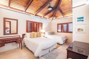 Une chambre avec deux lits, des poutres apparentes en bois au plafond, un bureau et un miroir.