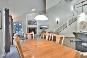 A dining area with a wooden table and chairs, a fireplace, and a staircase leading to another level. - True Ski-In/Ski-Out on 4 O’Clock Run | Tyra Summit (Breckenridge)