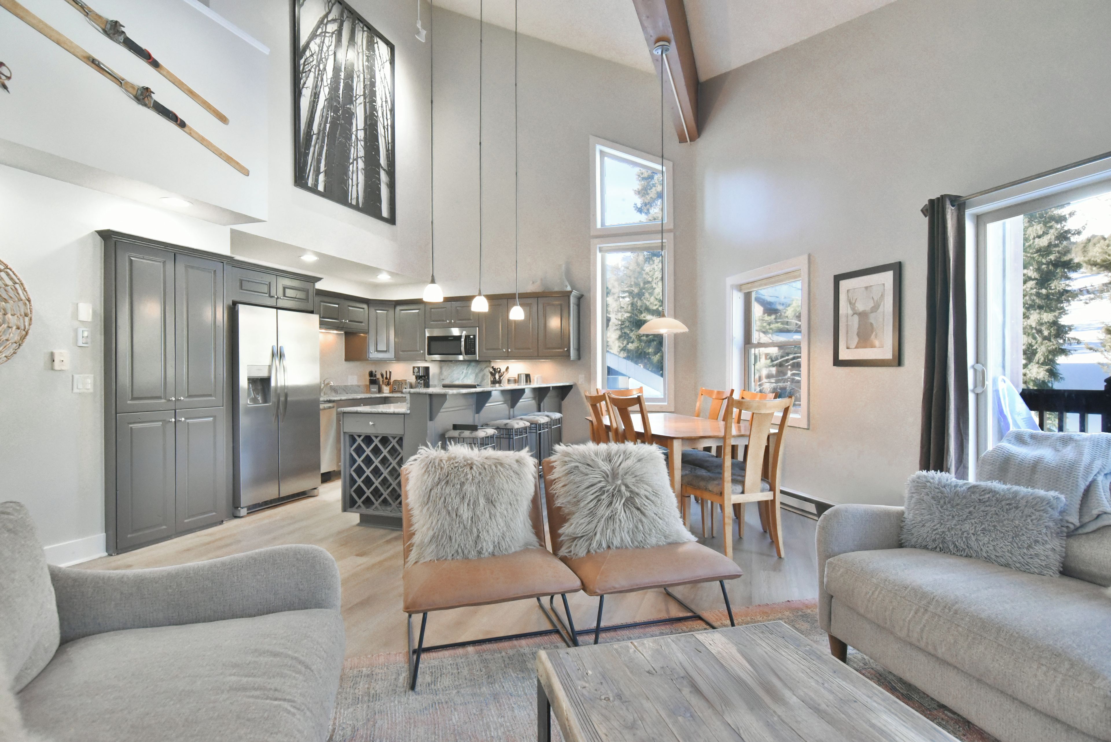 A modern kitchen with stainless steel appliances, a dining area with wooden chairs, and a cozy seating area with plush cushions.