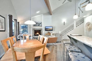 A modern interior with a dining area, fireplace, and a staircase leading to an upper level. - True Ski-In/Ski-Out on 4 O’Clock Run | Tyra Summit (Breckenridge)