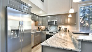 Una cocina moderna con electrodomésticos de acero inoxidable, encimeras de granito y un amplio ventanal que proporciona luz natural.