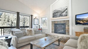 Una sala de estar acogedora con chimenea, ventanas amplias y un espacio de descanso confortable.