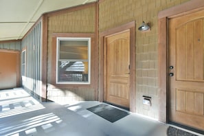 A hallway with a wooden door, a window, and a wall with a brick pattern.