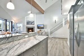 A modern kitchen with a marble countertop, a built-in stove, and a stainless steel refrigerator.