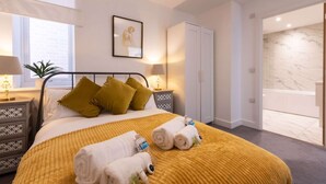 Una camera d'albergo con un letto, due comodini, un armadio e un bagno visibile attraverso una porta aperta.
