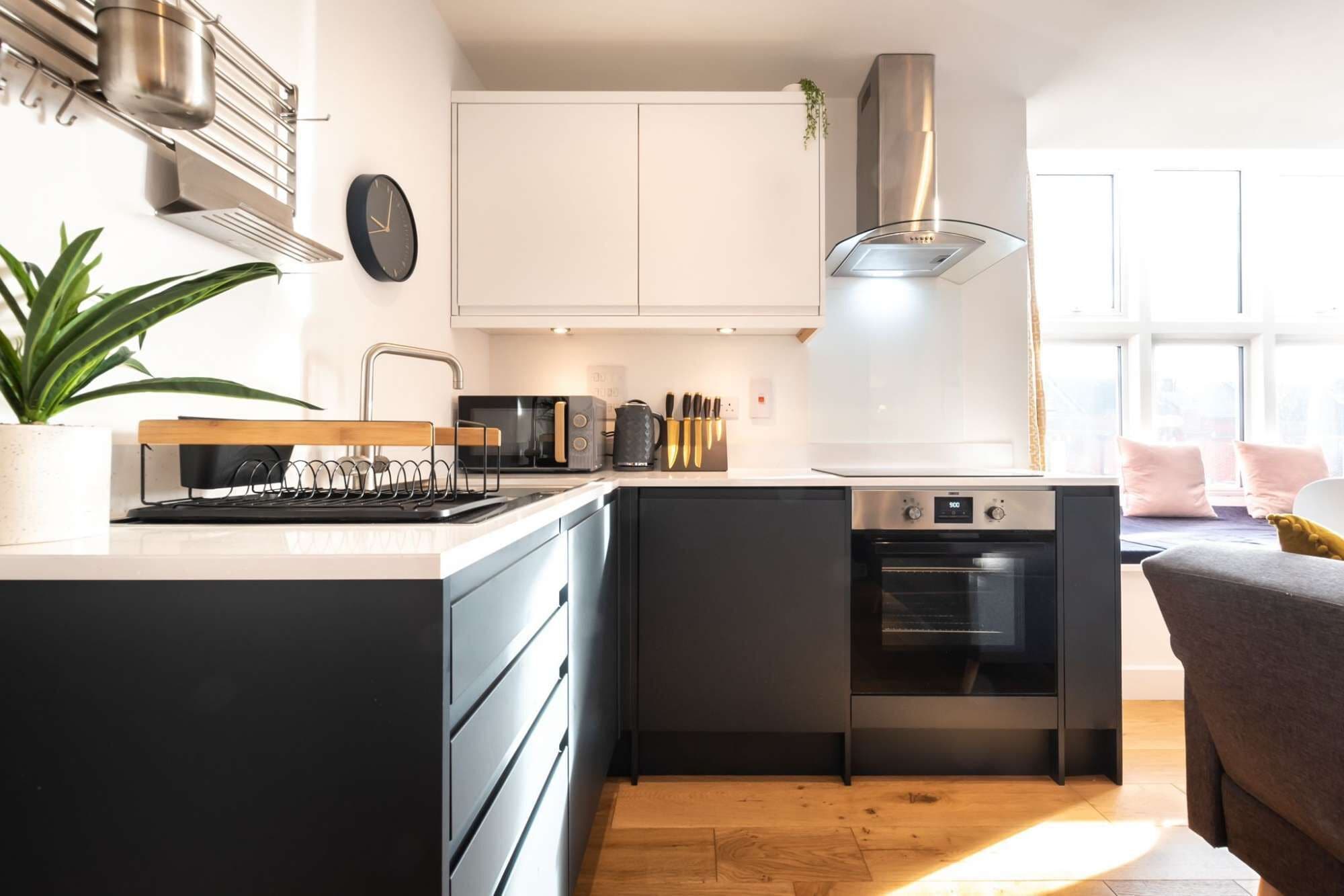 A modern kitchen with a built-in oven, a coffee machine, and a kettle on the countertop.