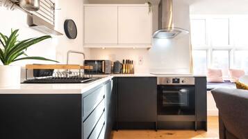 A modern kitchen with a built-in oven, a coffee machine, and a kettle on the countertop.