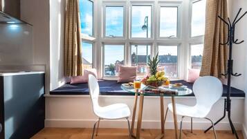 A breakfast setup with a table, chairs, and a view through a bay window.
