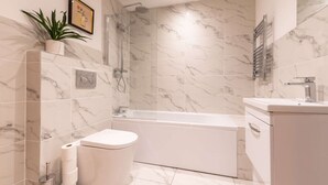 Un bagno moderno con toilette, bidet, doccia e vasca, il tutto rivestito in marmo.