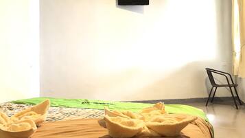 Une chambre d’hôtel avec un lit, une couverture verte, une couverture marron et des serviettes sur le lit.