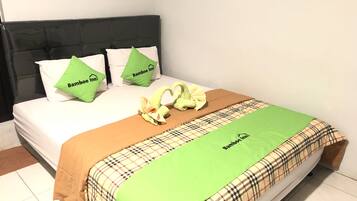 Una cama con un edredón escocés, dos almohadas verdes y una manta marrón.