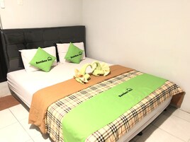 Una cama con un edredón escocés, dos almohadas verdes y una manta marrón.
