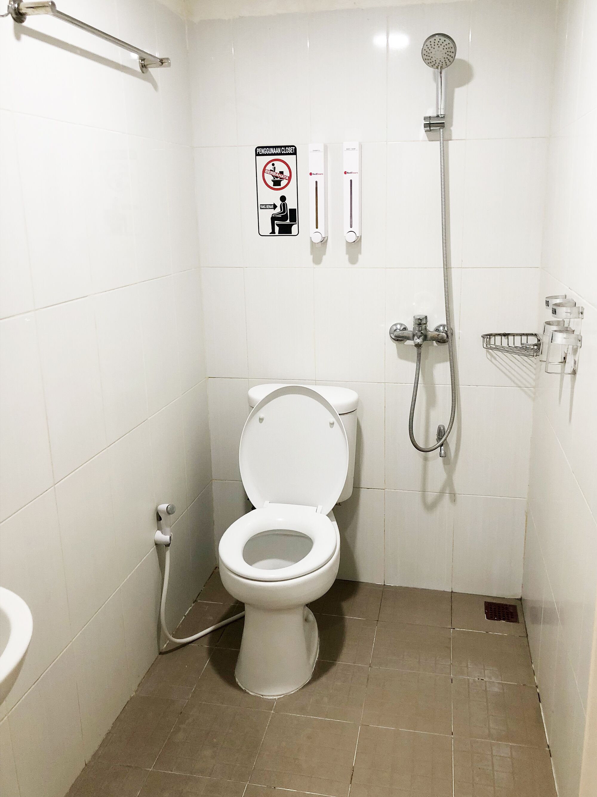 Un baño pequeño y limpio con inodoro, ducha y secamanos.