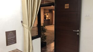 A hotel entrance with a wooden door labeled "102" and a reception area visible through the doorway. - Bamboe Inn 2 Homestay (Bandar Lampung)