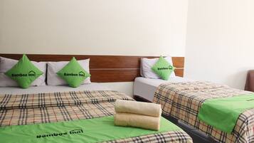 Habitación de hotel con dos camas, cada una con cubrecama escocés y almohadas verdes con el logo del hotel.