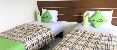 Two twin beds with plaid bedding and green throw pillows, each with a 'Bamboo Inn' logo.