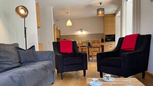 A modern living room with a sofa, two armchairs, a coffee table, and a magazine.