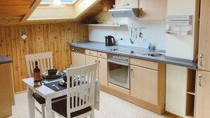 Ett kompakt kök med träskåp, ett takfönster, ett matbord med stolar och grundläggande köksutrustning.