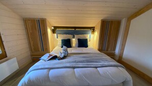 Un dormitorio acogedor con una cama grande, una mesita con un libro y una ventana a un lado.
