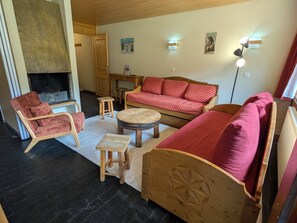 A cozy living room with a sofa, chairs, a small table, and a fireplace.