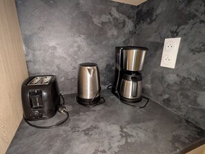 A kitchen counter with a toaster, a kettle, and a coffee maker.