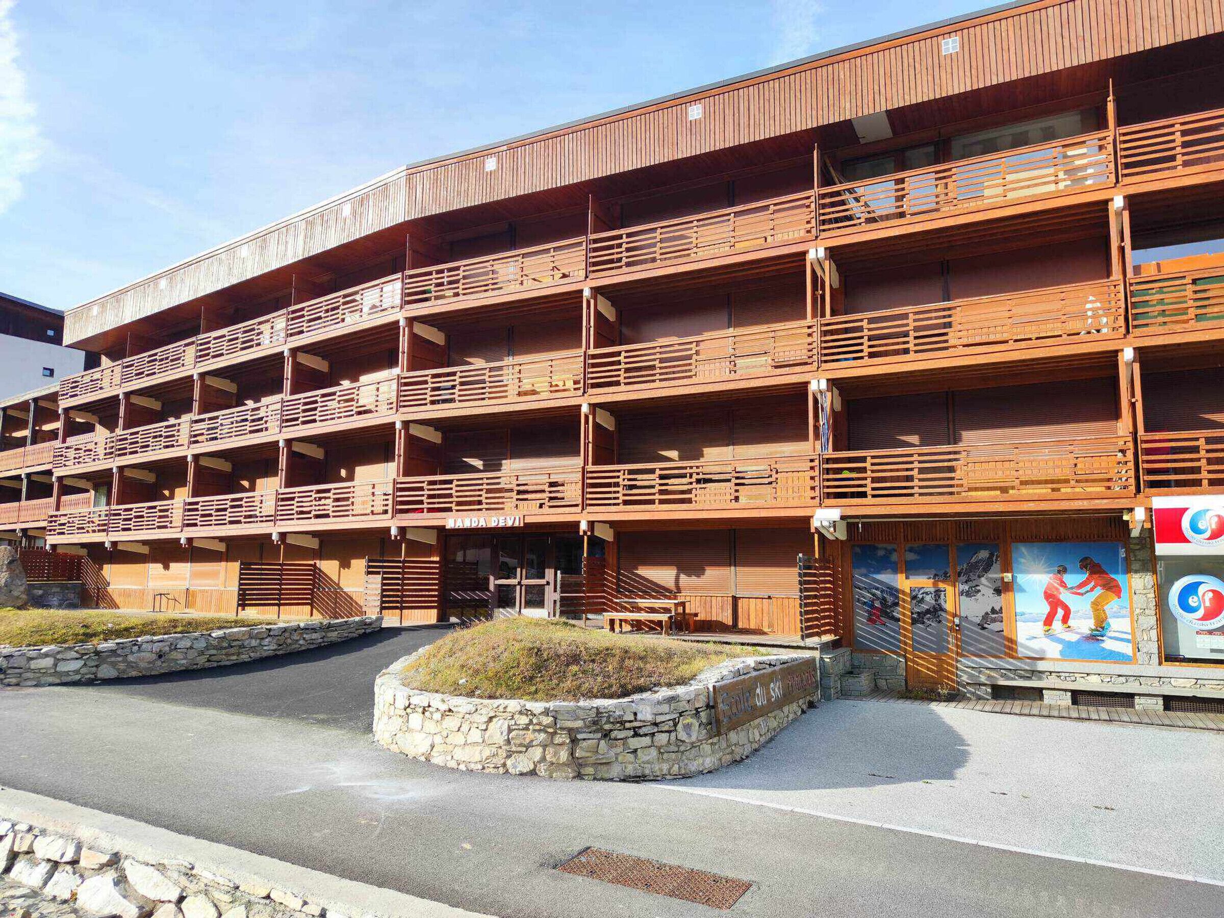 Un edificio de madera de varios pisos con balcones, una pared de piedra y el letrero de un complejo de esquí.