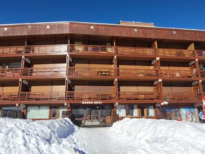 A multi-story hotel with balconies and a snow-covered ground. - Large South Apt · Ski-in/out · Balcony · 8 pers. (La Plagne)