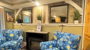 A living room with two blue armchairs, a fireplace, a mirror, and a framed welcome sign. -  Amazing Suite w Fireplace & Washer & Dryer! Pets & 420 Friendly (Gatlinburg)